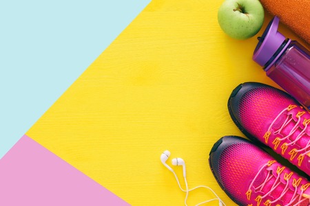 fitness concept with bottle of water, towel and woman pink sport footwear over colorful background.の写真素材