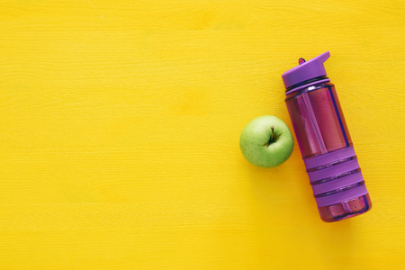 fitness concept with bottle of water and apple over colorful background.の写真素材