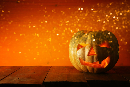 Halloween Pumpkin on wooden table in front of spooky dark background. Jack o lantern.の写真素材