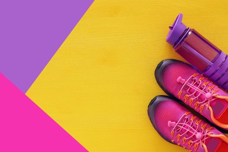 fitness concept with bottle of water and woman pink sport footwear over colorful background.の写真素材