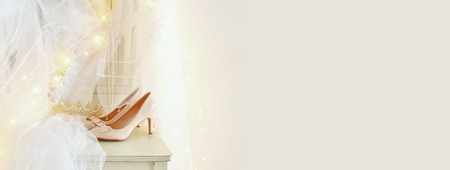 Beautiful white wedding dress and veil on chair with gold garland lights.の写真素材