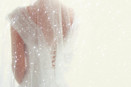 Dreamy abstract and blurry background of beautiful bride with wedding dress, from behind. Glitter overlayの写真素材