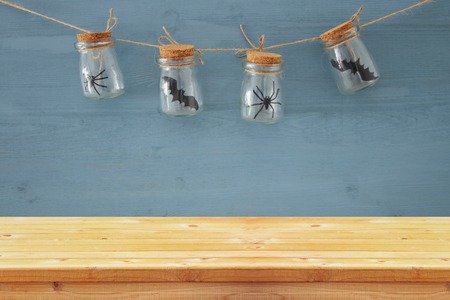 Halloween holiday concept. Empty old wooden table in front of masson jars with spiders and baths decorations. Ready for product display montageの写真素材