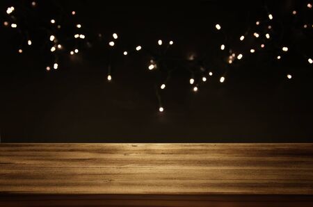 Empty table in front of black and gold glitter garland lights background. For product display...