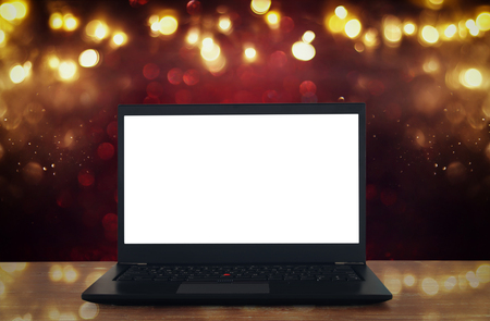 Image of open laptop with white screen on wooden table in front of abstract glitter background.の写真素材