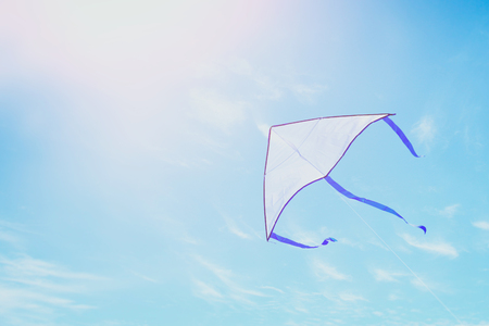 Colorful kite flying in the blue sky through the clouds.の写真素材