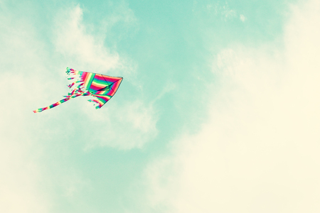 Colorful kite flying in the blue sky through the clouds.の写真素材