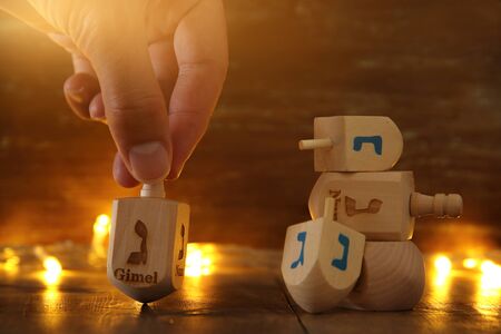 Image of jewish holiday Hanukkah with wooden dreidels colection (spinning top) and gold garland lights on the table.の写真素材