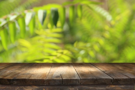 wooden table in front of tropical green floral background. for product display and presentationの写真素材