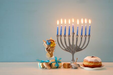 image of jewish holiday Hanukkah background with traditional spinnig top, menorah (traditional candelabra) and burning candlesの写真素材