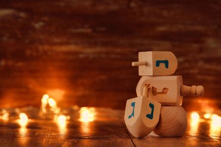 Image of jewish holiday Hanukkah with wooden dreidels colection (spinning top) and gold garland lights on the tableの写真素材