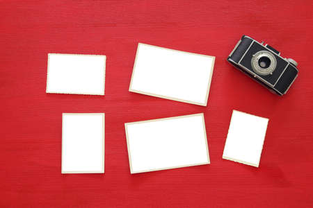 Top view image of old camera and empty photo frames on red wooden background. Flat lay. For photography and scrapbook montageの写真素材
