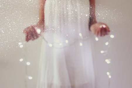 Abstract and bokeh image of young woman holding garland christmas lightsの写真素材