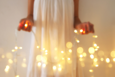 Abstract and bokeh image of young woman holding garland christmas lightsの写真素材