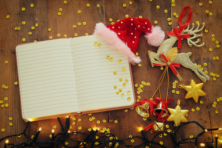 Top view image of christmas festive decorations next to empty open notebook on old wooden background. Ready for adding text or mockupの写真素材