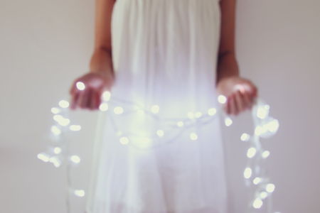 Abstract and bokeh image of young woman holding garland christmas lightsの写真素材
