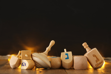 Image of jewish holiday Hanukkah with wooden dreidels colection (spinning top) and gold garland lights on the tableの写真素材