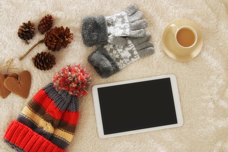 Cup of coffee next to tablet device with empty screen over cozy and warm fur carpet. Top viewの写真素材