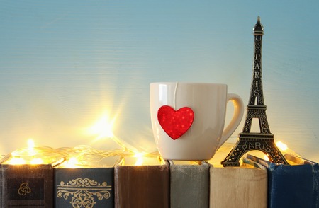 Valentine's day background. Cup of coffee or tea next to eiffel tower over old booksの写真素材