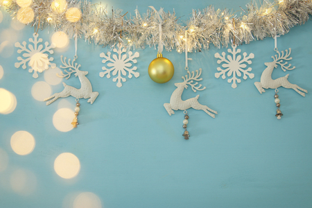 Christmas background with tree festive garland, white deer, and paper white snowflakes over light blue backgroundの写真素材