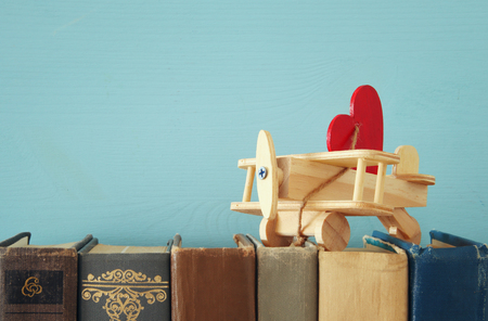 Valentine's day background. Wooden toy plane with heart over old booksの写真素材