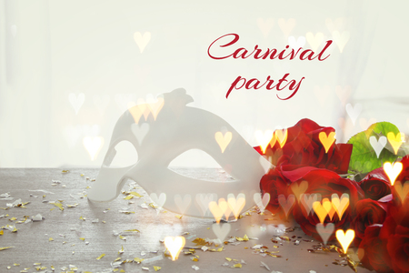 Image of elegant venetian mask and red roses on wooden table.の写真素材