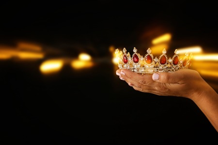 Woman's hand holding a crown for show victory or winning first place. Glitter overlayの写真素材