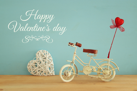 Valentine's day romantic background with white vintage bicycle toy and glitter red heart on it over wooden tableの写真素材