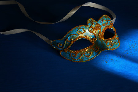 Image of elegant blue and gold venetian, mardi gras mask over dark background. Vintage filtered photoの写真素材