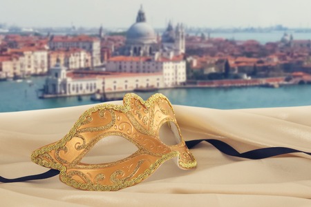 Image of elegant venetian mask on silk fabric in front of blurry Venice background.の写真素材