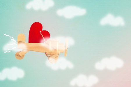Valentine's day background. Wooden toy plane with heart flying in the skyの写真素材