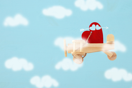 Valentine's day background. Wooden toy plane with heart flying in the skyの写真素材