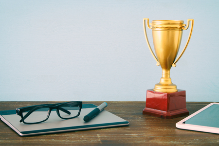 Top view imago of office table with the digital items golden Trophy. Business excellence conceptの写真素材