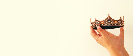 Woman's hand holding a crown for show victory or winning first place. White background. Copy space. Isolatedの写真素材