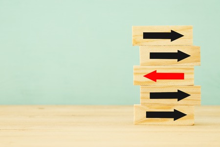 Unique red arrow brick among many black ones. Standing out from crowd, individuality and difference conceptの写真素材