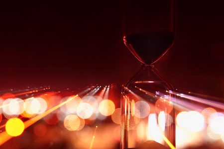 Hourglass over bokeh city lights as time passing concept for business deadlineの写真素材