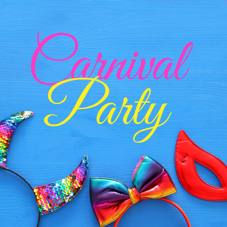 Top view image of carnival masquerade accessories: colorful and funny devil horns, hair bow and red mask over woodeb blue backgroundの写真素材