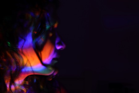 abstract portrait of young girl under colorful fluorescent Neon dark lights, enigmatic styleの写真素材