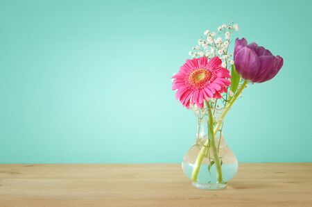 summer bouquet of flowers over wooden table with mint background