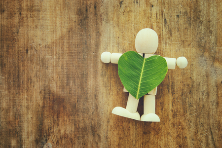wooden person holding a heart shaped leaf. ecology and recycling conceptの写真素材