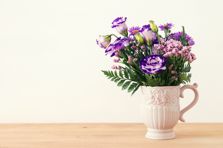 summer bouquet of purple flowers in the vase over wooden table and white backgroundの写真素材