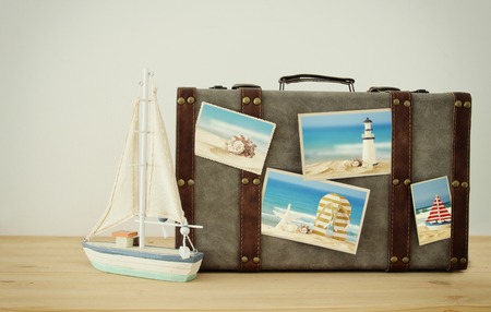 Image of old vintage luggage with vacation photos over wooden floorの写真素材