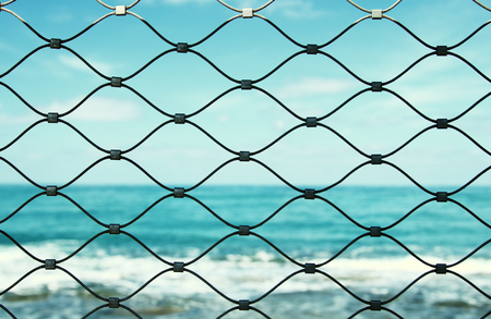 Barbed wire - restricted area and sea in the horizon.の写真素材