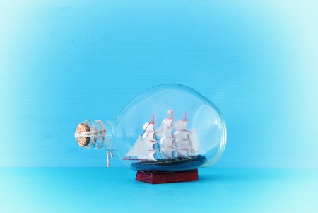 nautical concept image with sail boat in the bottle over blue wooden table and background. Selective focusの写真素材