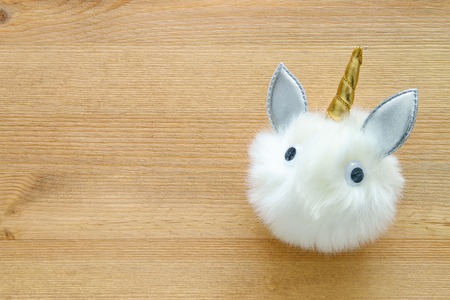 Cute fur ball unicorn with over wooden backgroundの写真素材