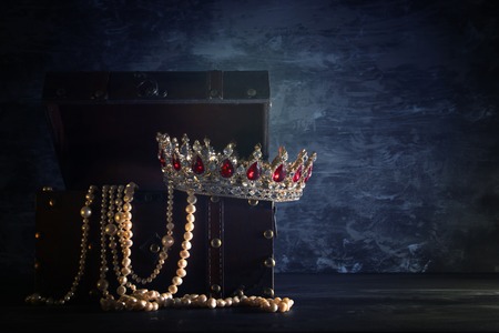 Image of mysterious opened old wooden treasure chest with light and queen/king crown with red Rubies stones. fantasy medieval period. Selective focus.の写真素材