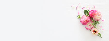 Image of delicate pastel pink beautiful flowers arrangement over white wooden background. Flat lay,...