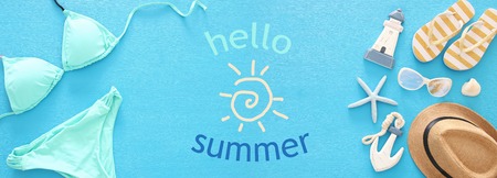 vacation and summer banner with sea life style objects and mint bikini over blue wooden background