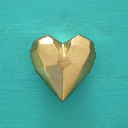 Golden heart over turquoise wooden background. Top viewの写真素材