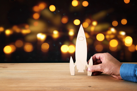 man's hand holding wooden rocket, over glitter black backgroundの写真素材